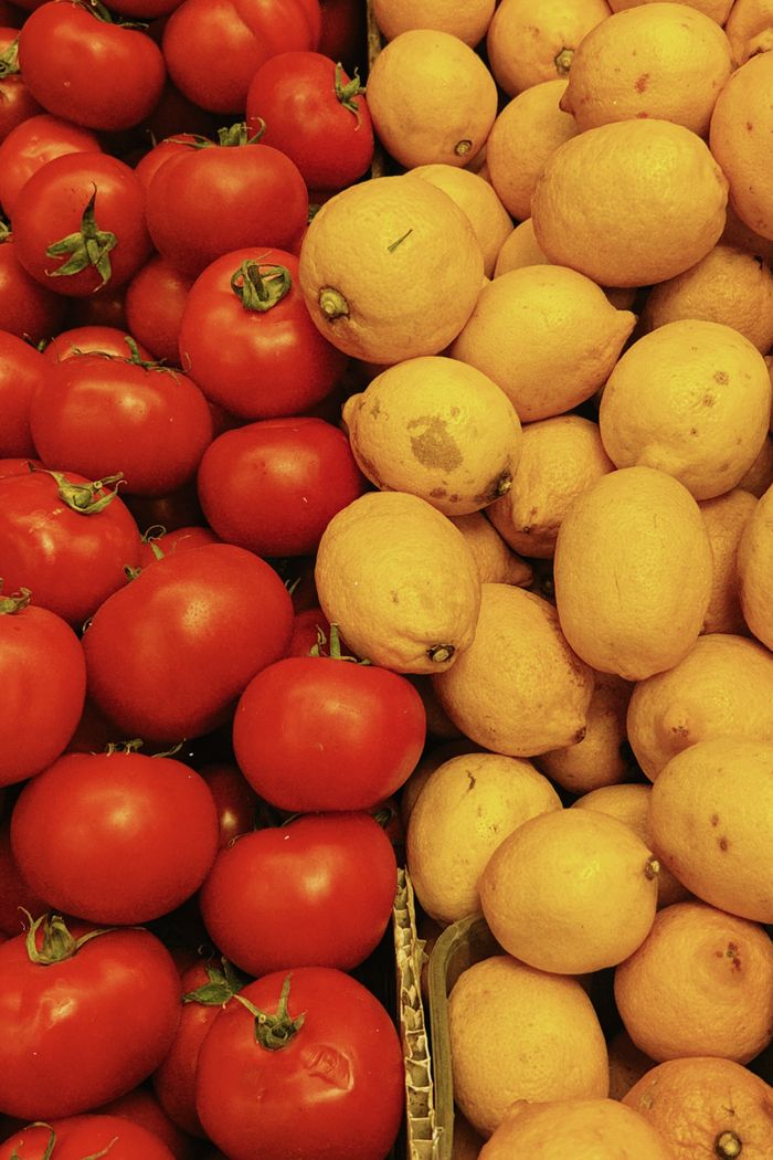 Vibrant display of fresh tomatoes and lemons at a market.