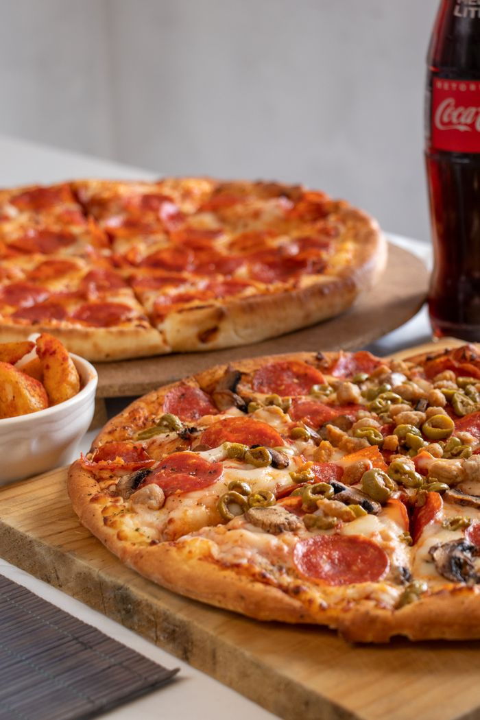Close-up of pepperoni and veggie pizzas with soda, perfect for a casual dining experience.